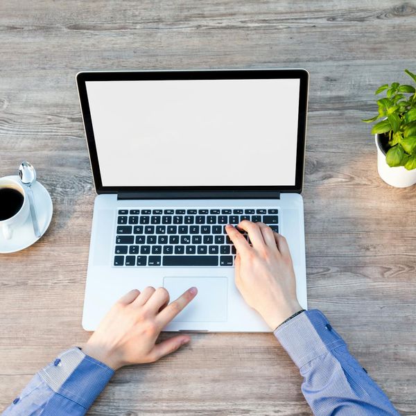 Person working comfortably at a minimalist desk with a green plant.