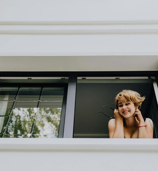 Smiling person looking out a window, feeling refreshed and energetic.